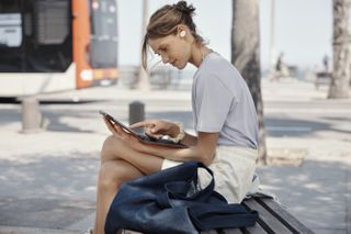 A person reading while listening to music with the JBL Tune 130NC earbuds