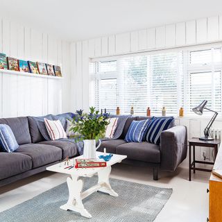 living room with white wall grey sofa with cushions and white window