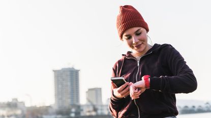 What is VO2 max, running heart-rate zones and lactate threshold: Pictured here, a female runner looking at her running watch and phone