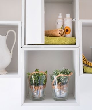 bathroom with white cabinets and shelves containing items