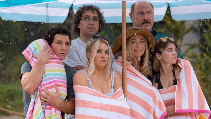 The Cooper and McAllister family under a large umbrella in the middle of a rainy day on the beach