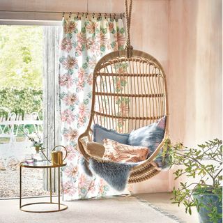 Bamboo chair with blue and pink cushions suspended from the ceiling