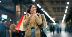 A happy woman carrying shopping bags over her shoulder.