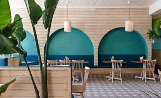 Wood designed dining area with green and blue recessed arch in wall designs, tables, chairs and hanging lights