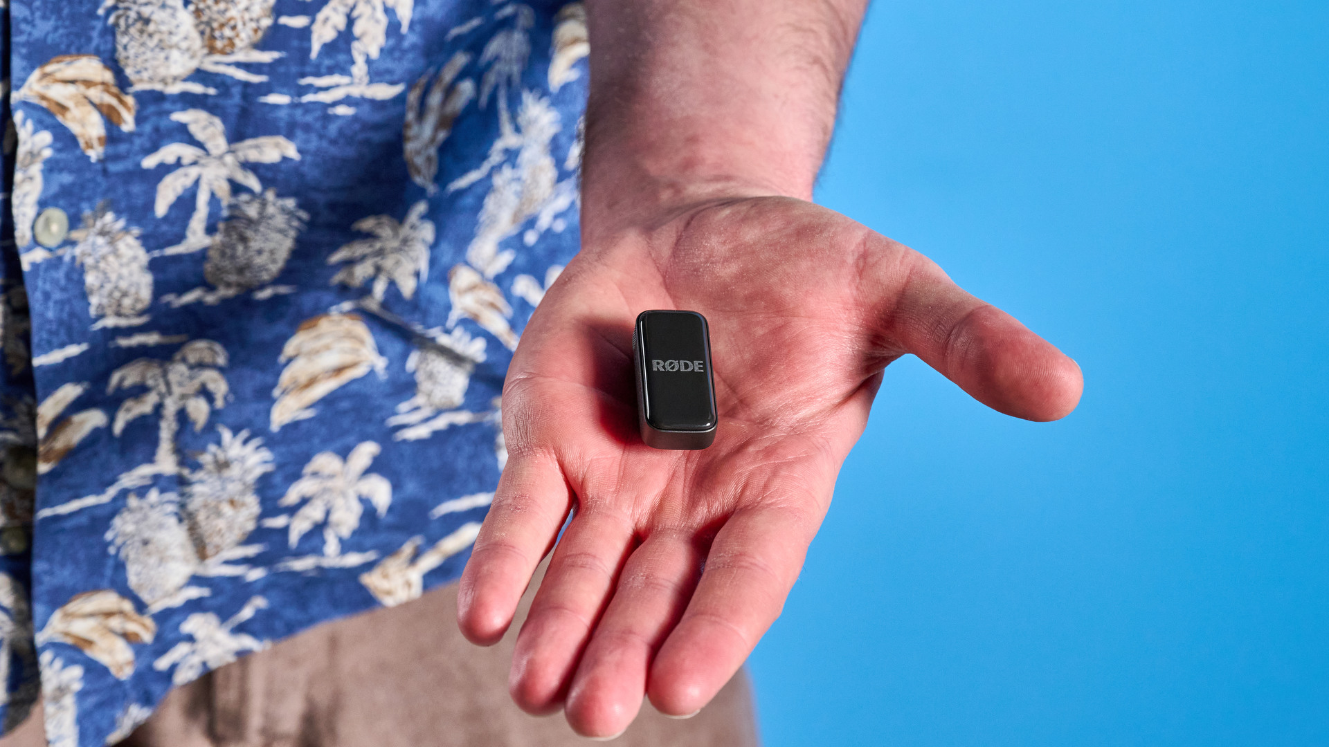 the rode wireless micro microphone with the black charging case and two black transmitter mics photographed against a blue background