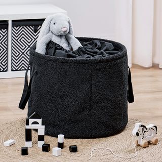 Black boucle storage with plush bunny inside and toys surrounding it