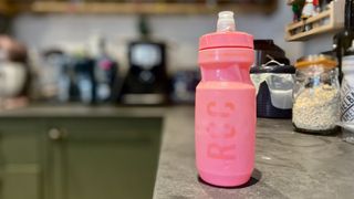 A well-used pink Camelbak Podium 21oz bottle stands on a kitchen surface