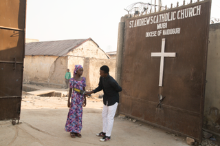 A guard checks a young girl for explosives at a Catholic church in Mubi