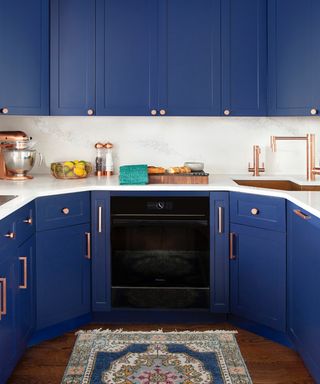 should I use handles or knobs on kitchen cabinets/blue and white kitchen with curved design, small kitchen, rug, copper knobs and handles