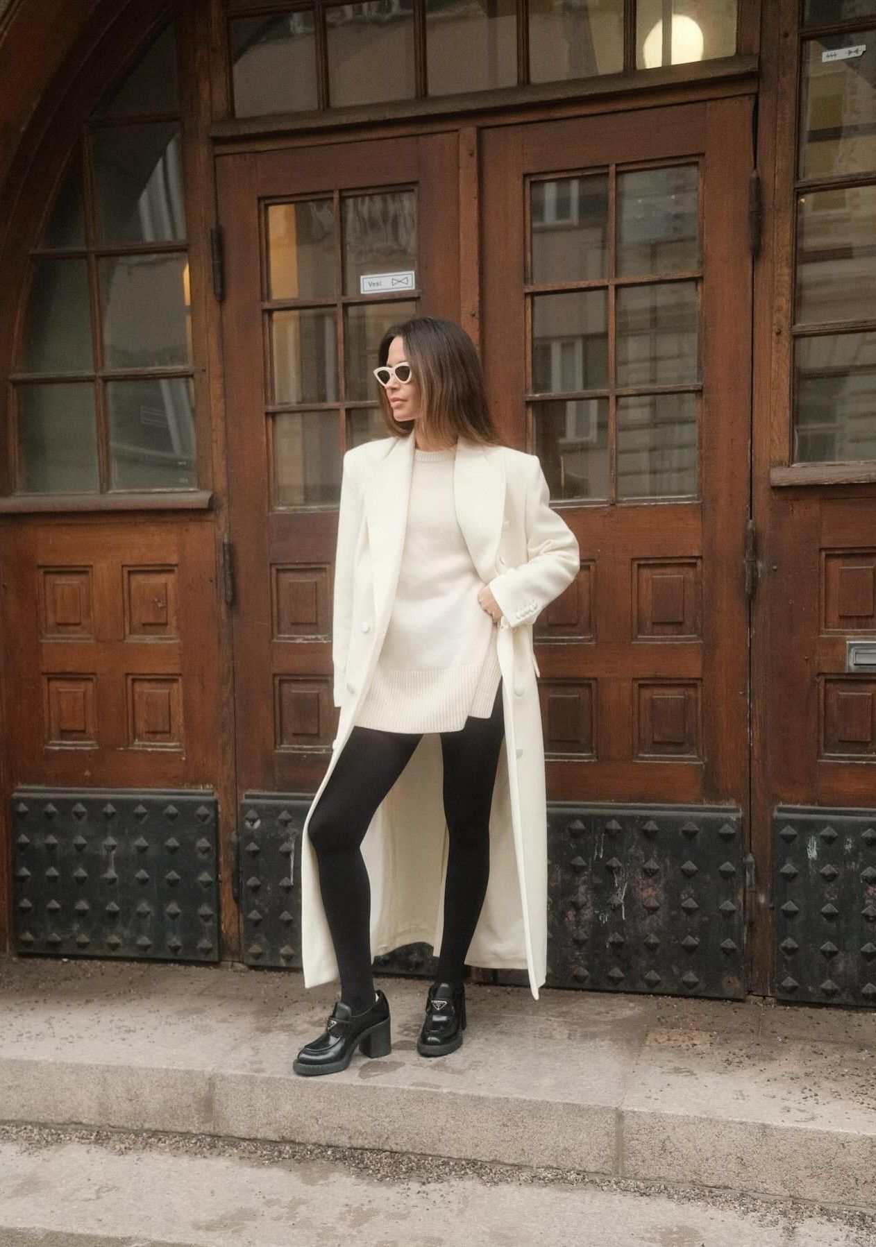 An image of @johannapiispa wearing a white trench coat, heeled loafers and leggings, one of the biggest winter trends to wear with leggings.