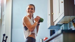 Woman making a smoothie in her kitchen before a workout: what to eat before a workout