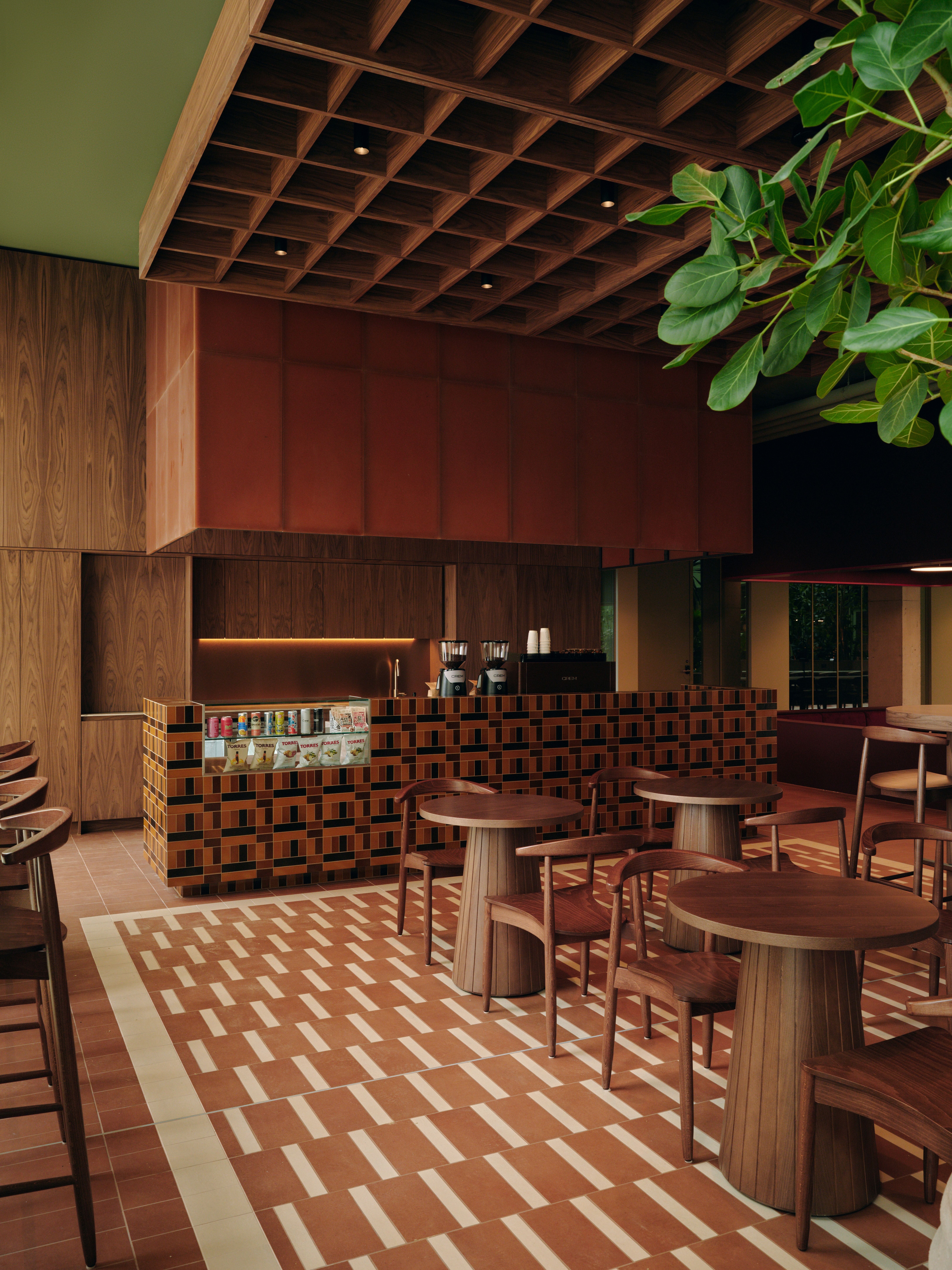 A series of interior shots of a workspace designed with terracotta-hued checkered floors, coffered ceilings in wood and back-lit blocks, pendant, see-through lighting, mid-century furniture, 