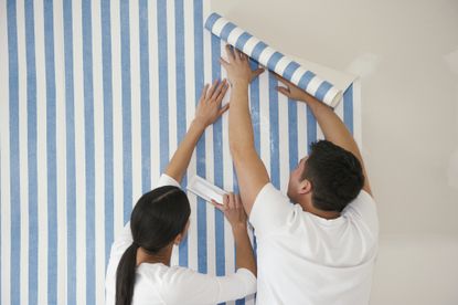 Couple putting up wallpaper, removable wallpaper