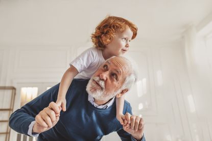 Grandfather giving piggyback ride to grandson at home