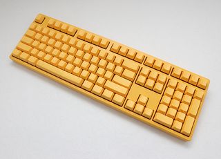 A yellow Ducky keyboard with very faint labels on its keycaps.
