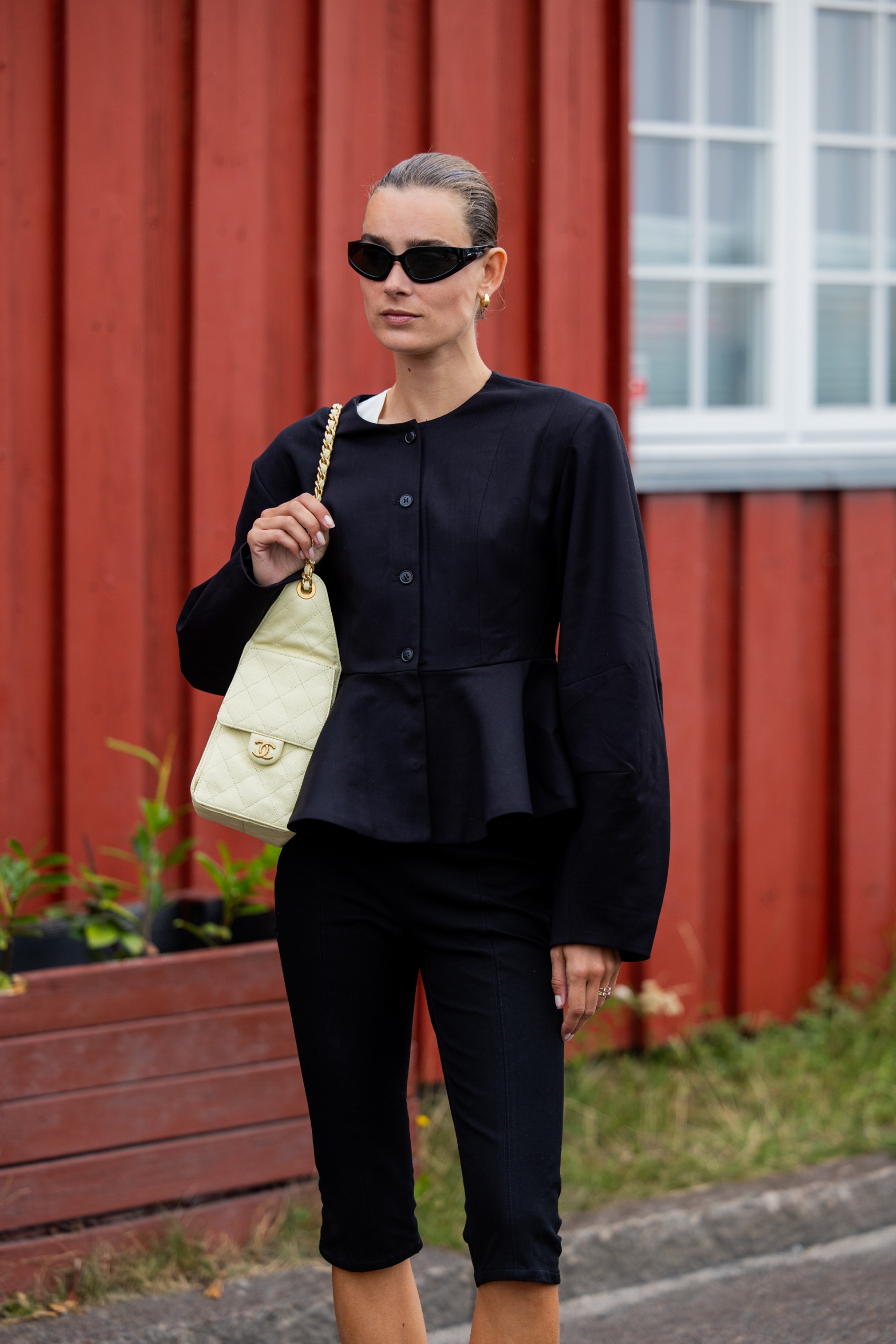 woman wears black collarless jacket and capri pants