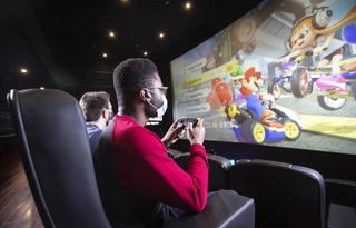 Two gamers look up and play on a huge cinema screen