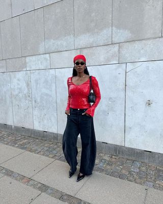 fashion influencer @nlmarilyn wearing a red sequin long sleeve top with black barrel-leg jeans in Copenhagen