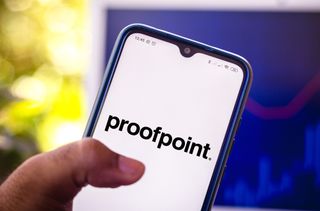A hand holding a smartphone displaying the Proofpoint logo