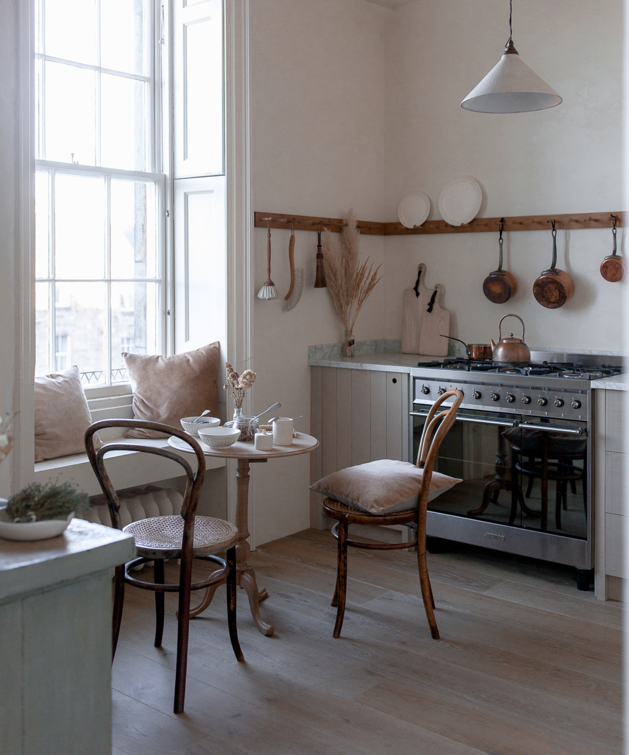 seating area in window space in small kitchen with wooden chairs and seat built out from windowsill