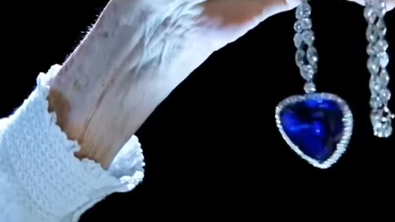 A hand holding the necklace called the heart of the ocean in Titanic