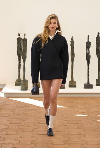 model wearing stylish outfit with socks, including a black blazer over button-down dress with white socks and loafers