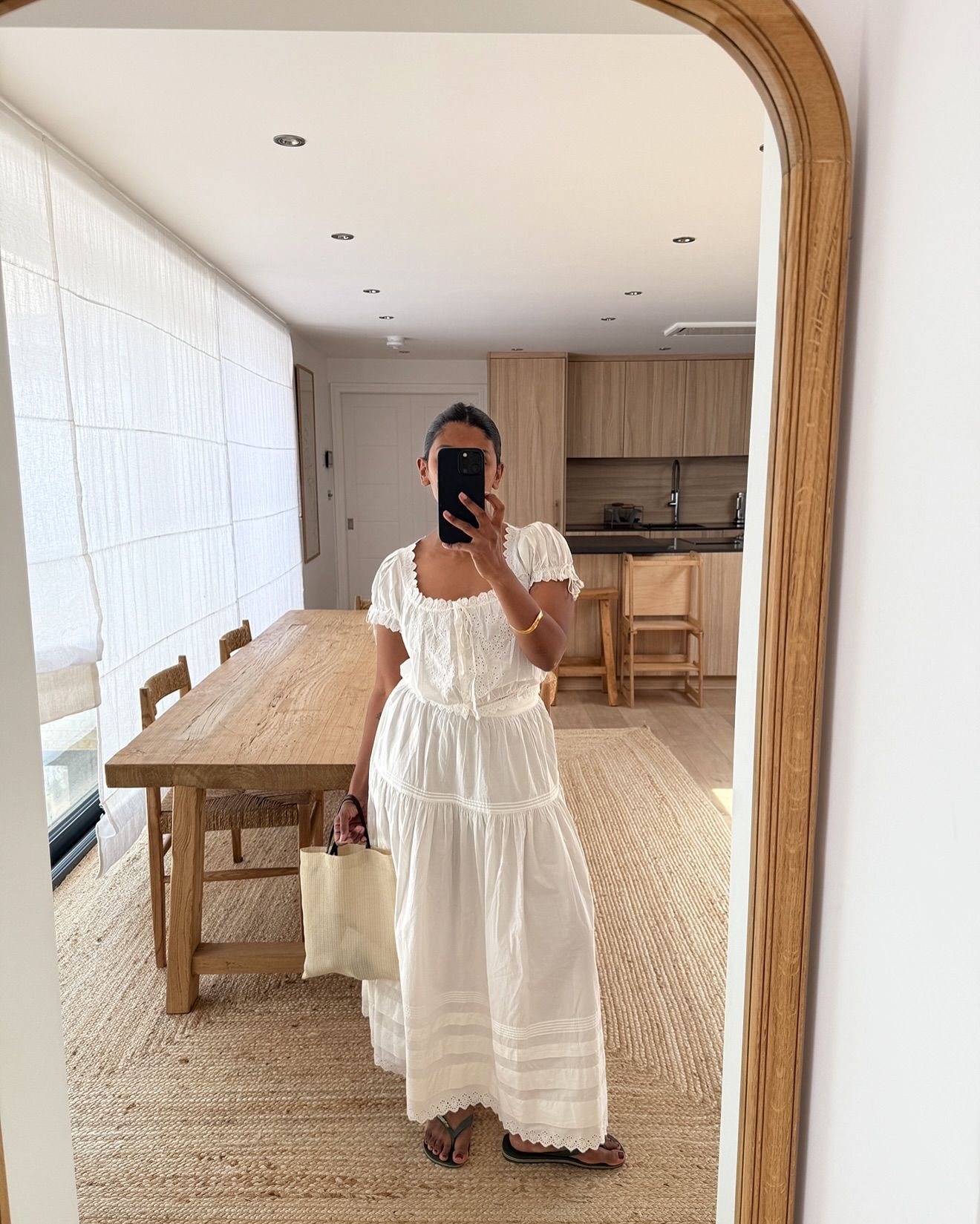 An image of @monikh wearing The Row's barn mesh tote bag with a pretty white nap dress.