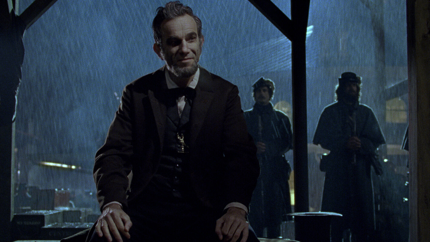 A still from the movie Lincoln in which Daniel Day-Lewis as Lincoln is sat in the rain.