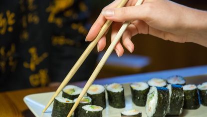 A pair of chopsticks with sushi