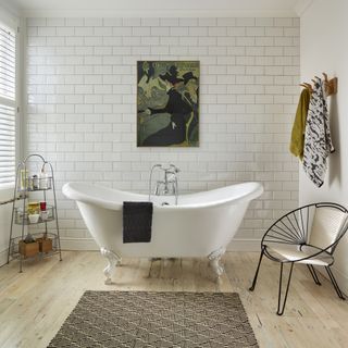 white metro tile bathroom framed artwork patterned rug freestanding rolltop bath soap shelf rack