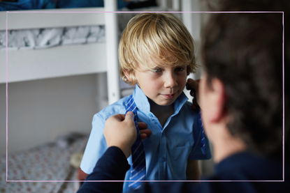 parent dressing boy in school uniform