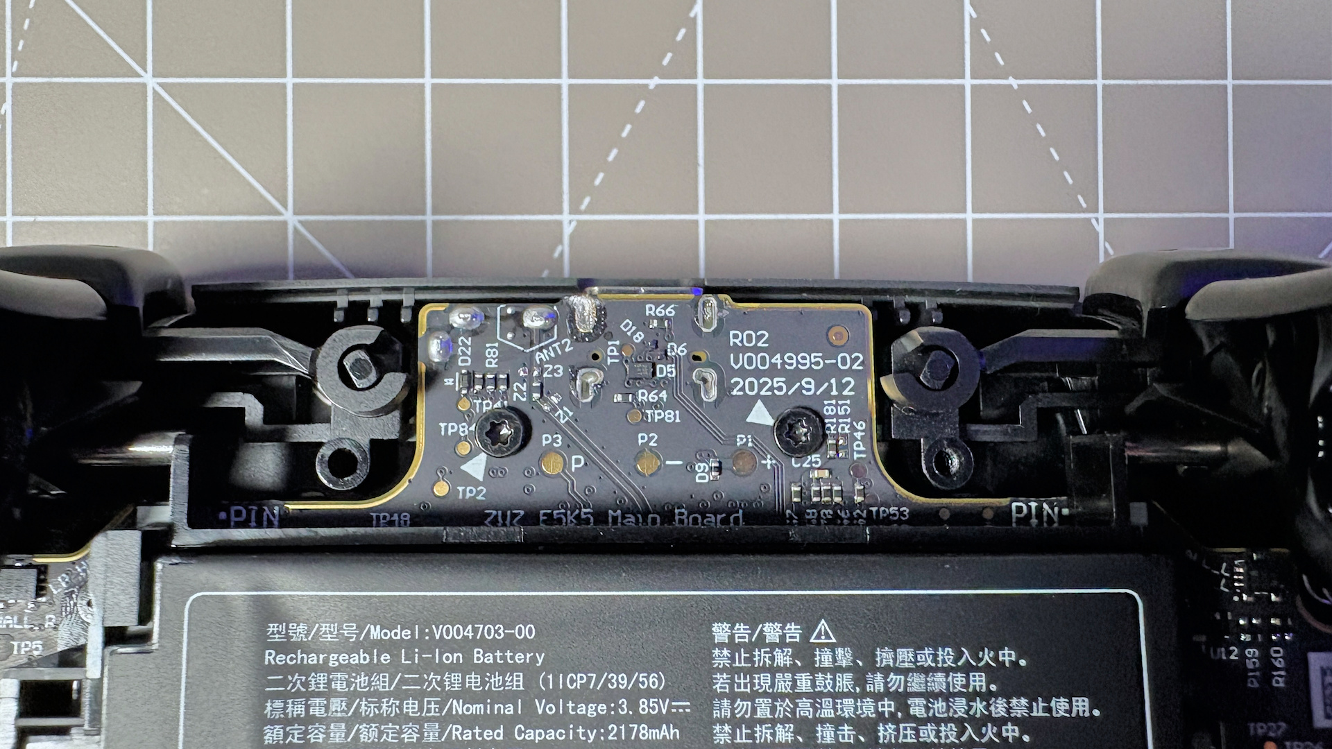 The Steam Controller on a desk during a teardown, with various parts removed.