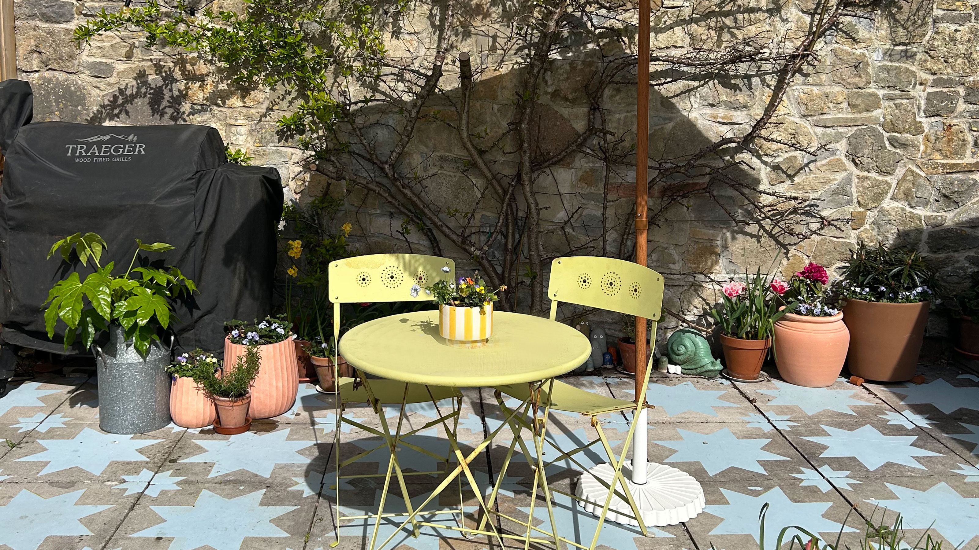 Patio with yellow bistro set, potted plants and slabs painted with blue star design
