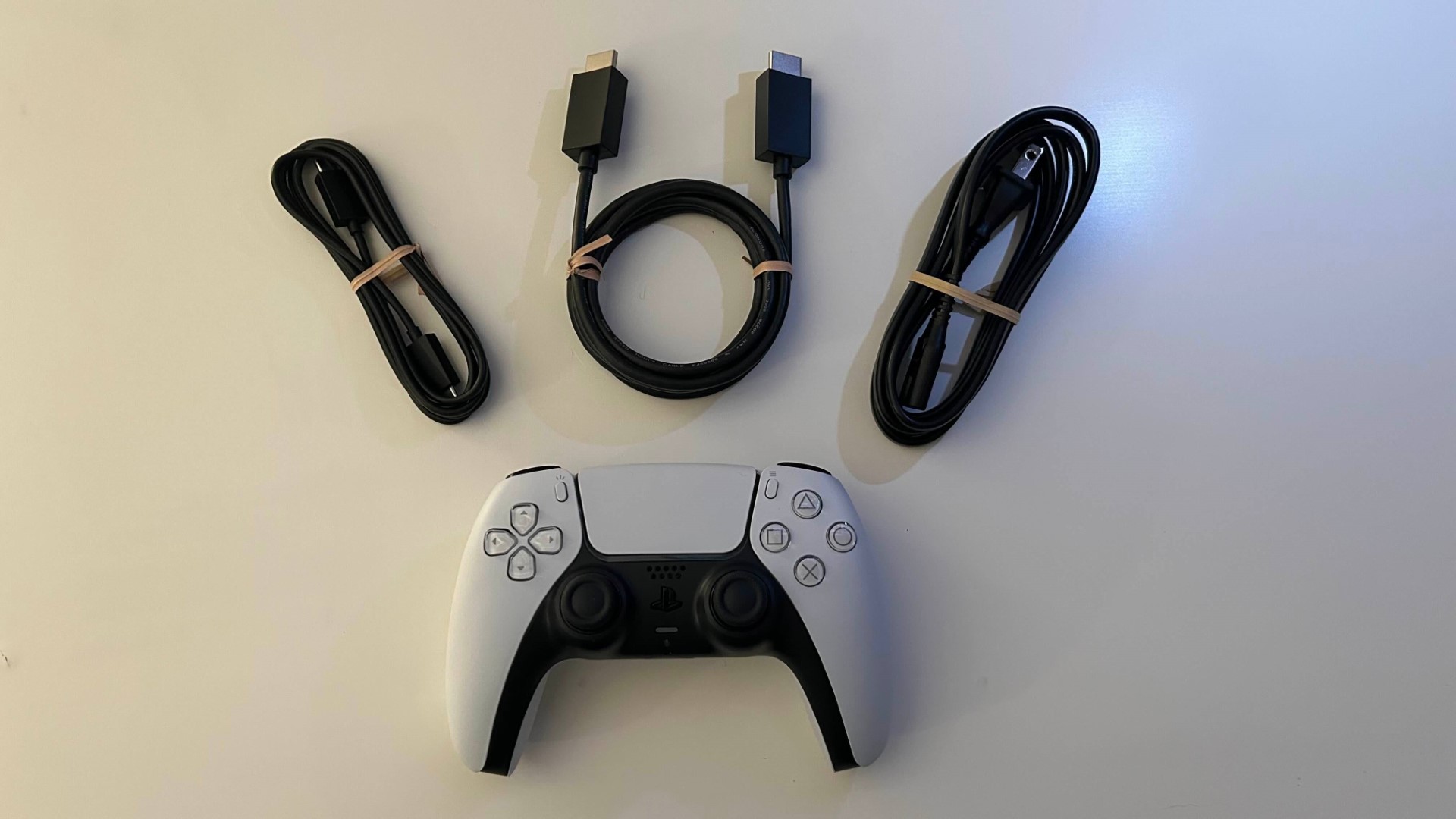 PlayStation 5 console controller and cables on a white desk