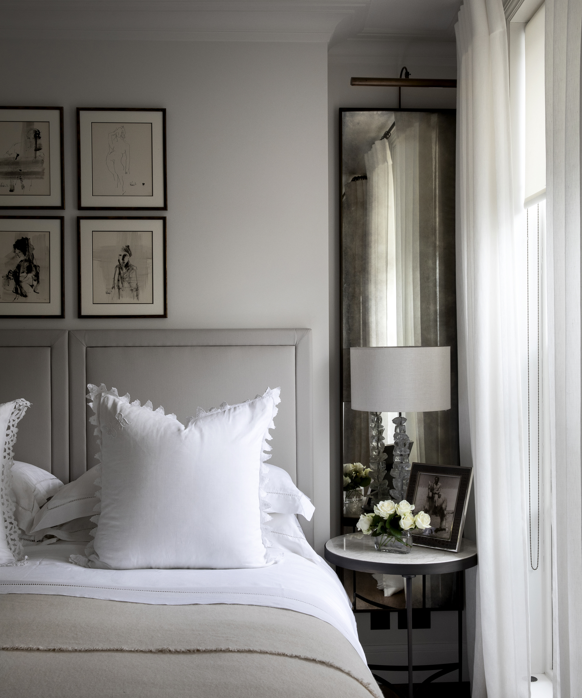 A white bedroom idea with pale grey headboard and tarnished mirror