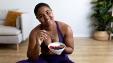 woman eats a bowl of yoghurt and fruit post workout