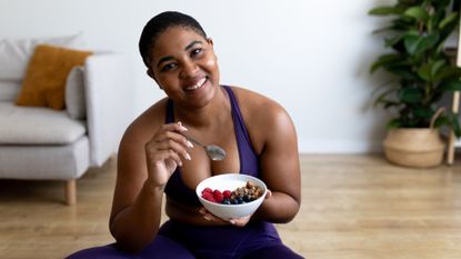 woman eats a bowl of yoghurt and fruit post workout