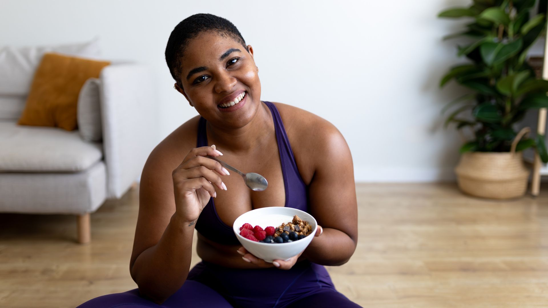 woman eats a bowl of yoghurt and fruit post workout