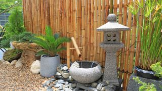 A bamboo fence and water feature in a Japanese garden