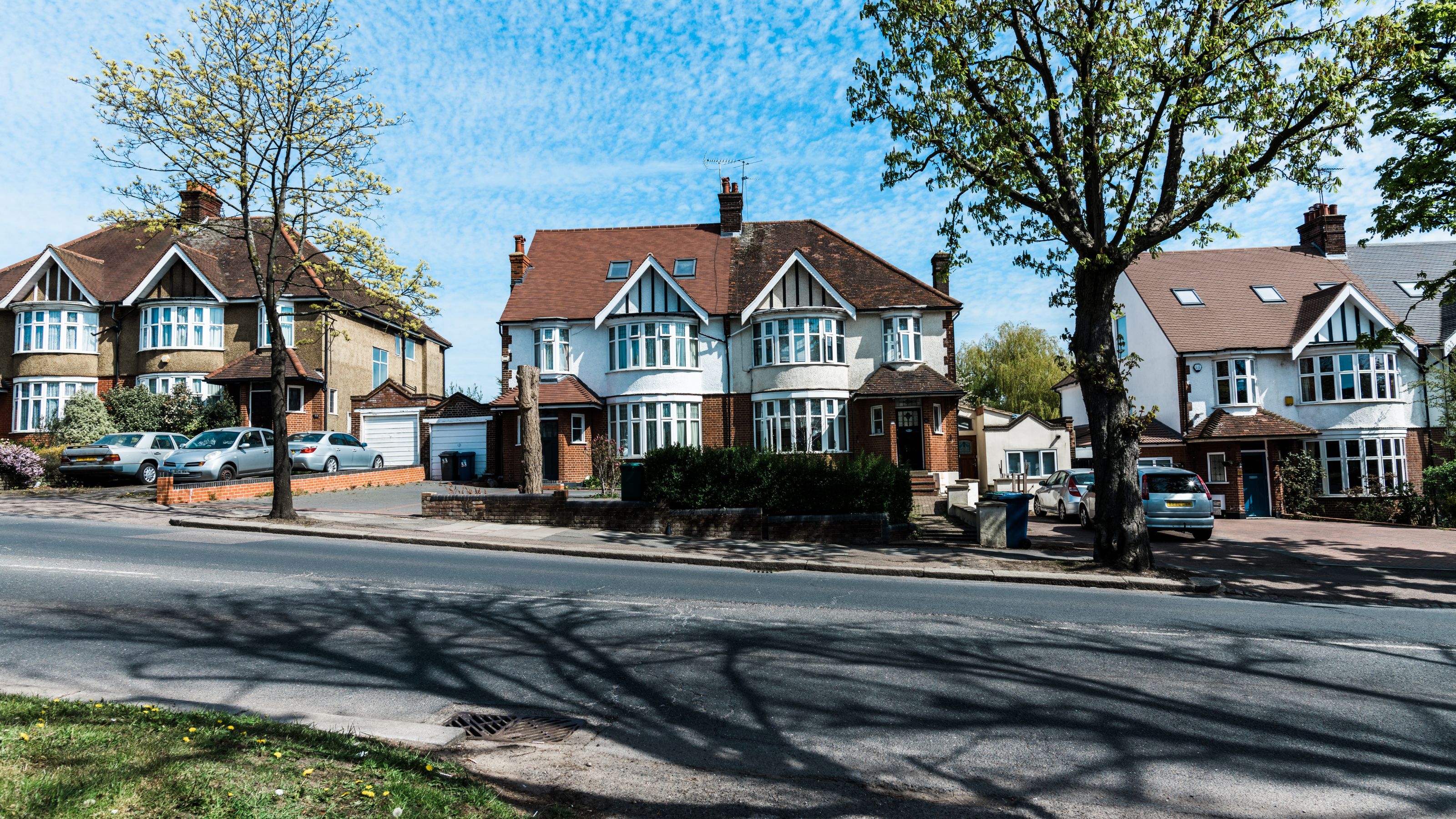 Street of semi-detached houses with tarmac driveways off a main road