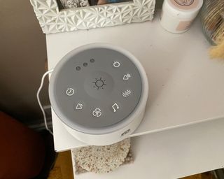 Dreamegg D1 white noise machine showing buttons sitting on white nightstand
