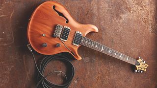 PRS guitar next to a coiled guitar cable