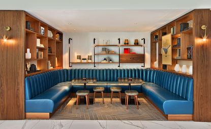 Lounge area of the Le Méridien Etoile hotel, Paris, France with wooden shelving, blue leather bench seats and grey stools