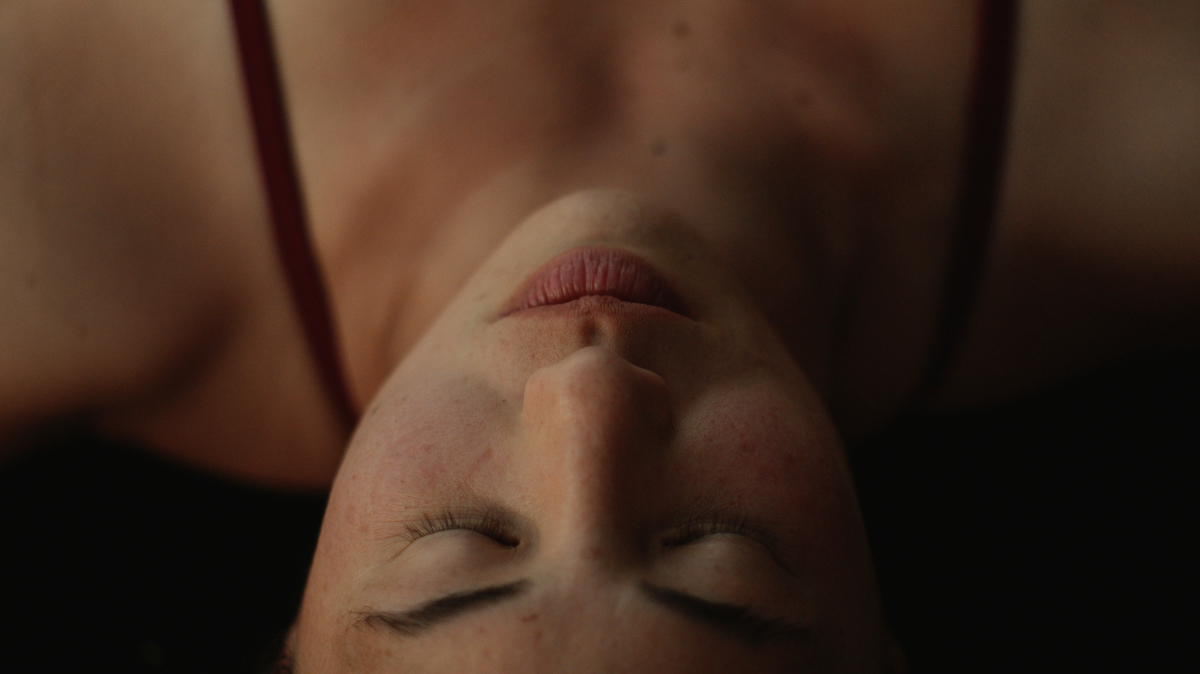 close-up of female diver's face, eyes closed, seen upside down
