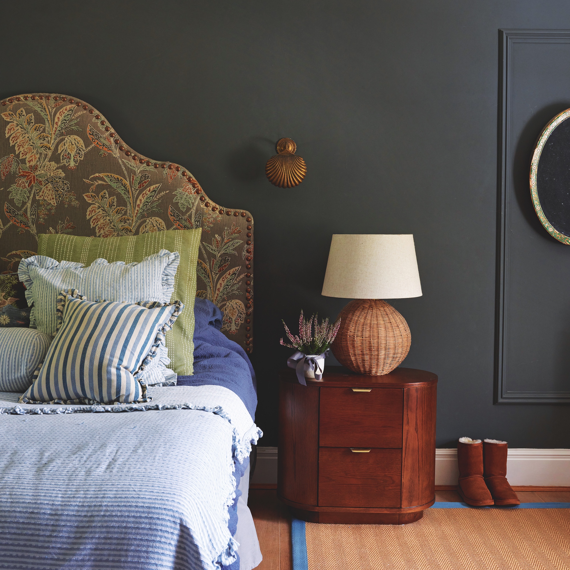 bedroom with black painted wall and bed with large upholstered headboard and blue and green pillows