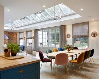 a garden room orangery extending out from a bright modern kitchen, with colorful dining chairs and wide floor-to-ceiling windows