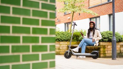 Woman sitting on a bench with a Pure Air Electric Scooter in front of her