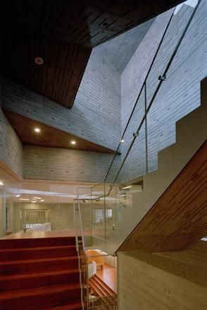 Interior of contemporary building showing a wide turning staircase - light natural colours blend with the light grey patterned concrete walls.