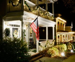 Christmas lights on homes with balconies and a US flag