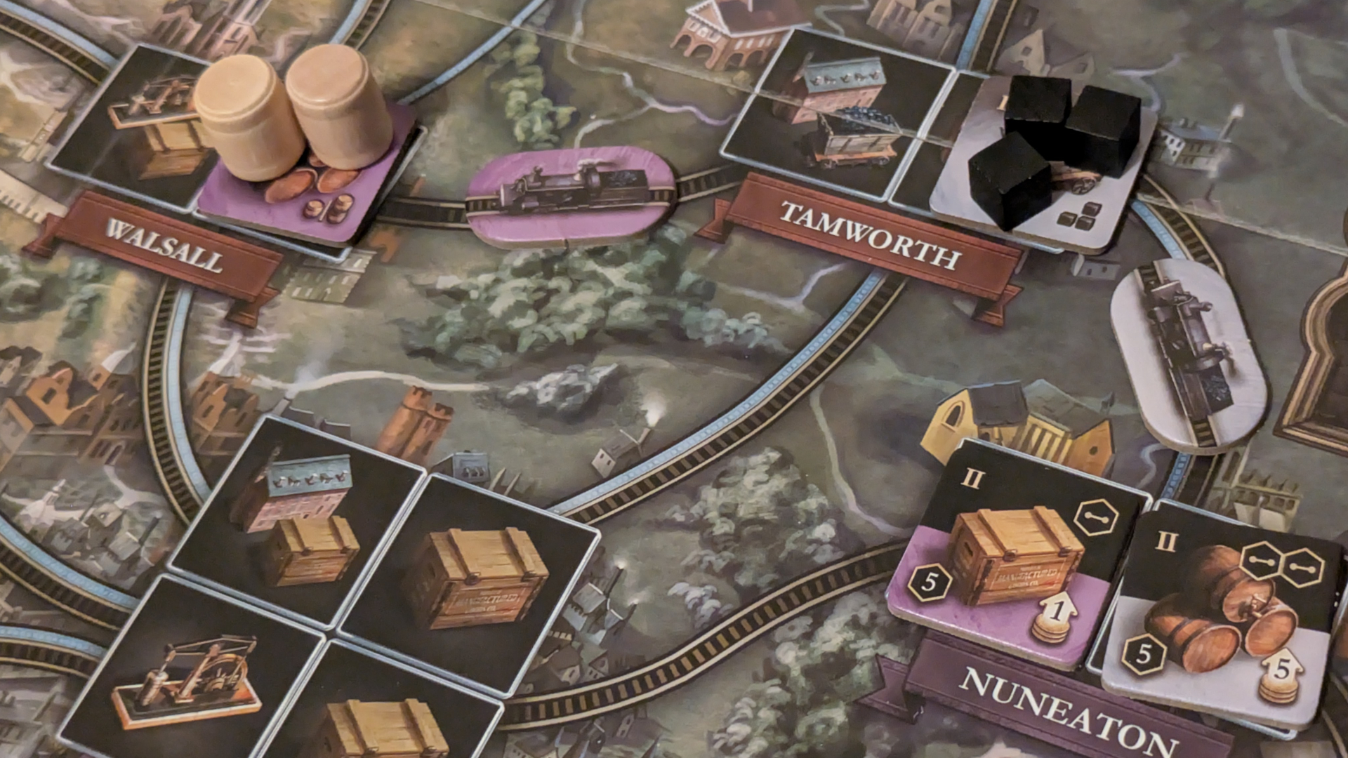 Crate, barrel, and train tokens laid out on the Brass: Birmingham board